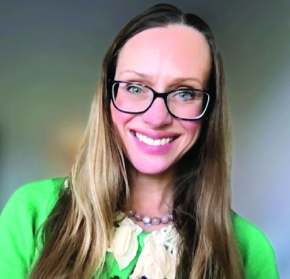 White woman in glasses smiling.